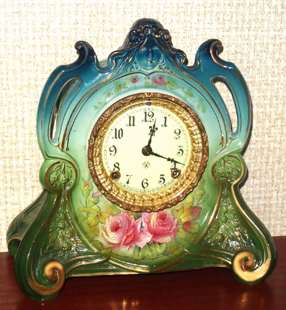 Ansonia Clock Co., C.1905, Royal Bonn, "LA CHAPELLE" porcelain china cased clock, with 8-day, gong strike mov't with one piece porcelain dial, in a multi-colored case, aqua at top, lime green center and dark green bottom, and with magenta colored blossoms below the dial. — Antique Clocks Price Guide