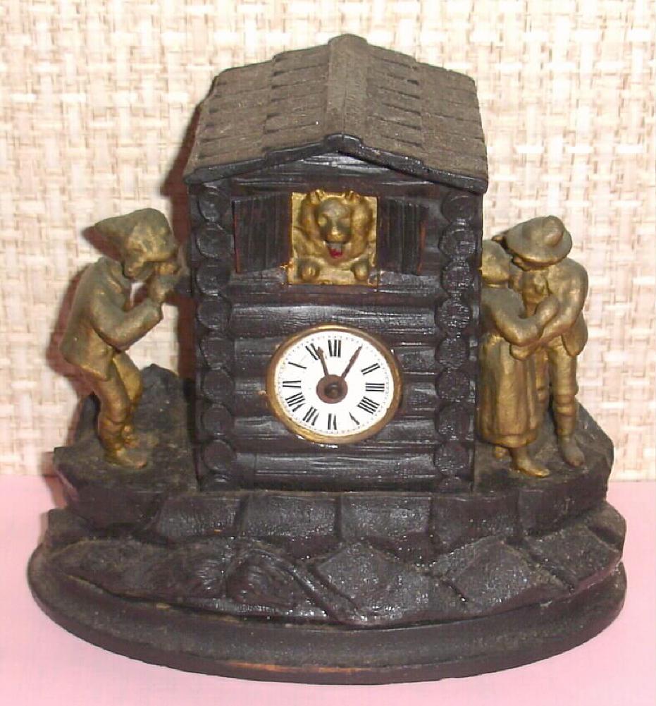 German, (Meyer?), Novelty Chalet Automaton, C.1875. Note the dog in center of log cabin has a panting tongue, and the man at the left has his head bobbing back and forth as he tries to see what is going on. Two lovers at right in romantic embrace. Like other clock in this series, this one utilizes a small, pendulette movement, with the dog's tongue and gents head attached by a wire to the verge. — Antique Clocks Price Guide