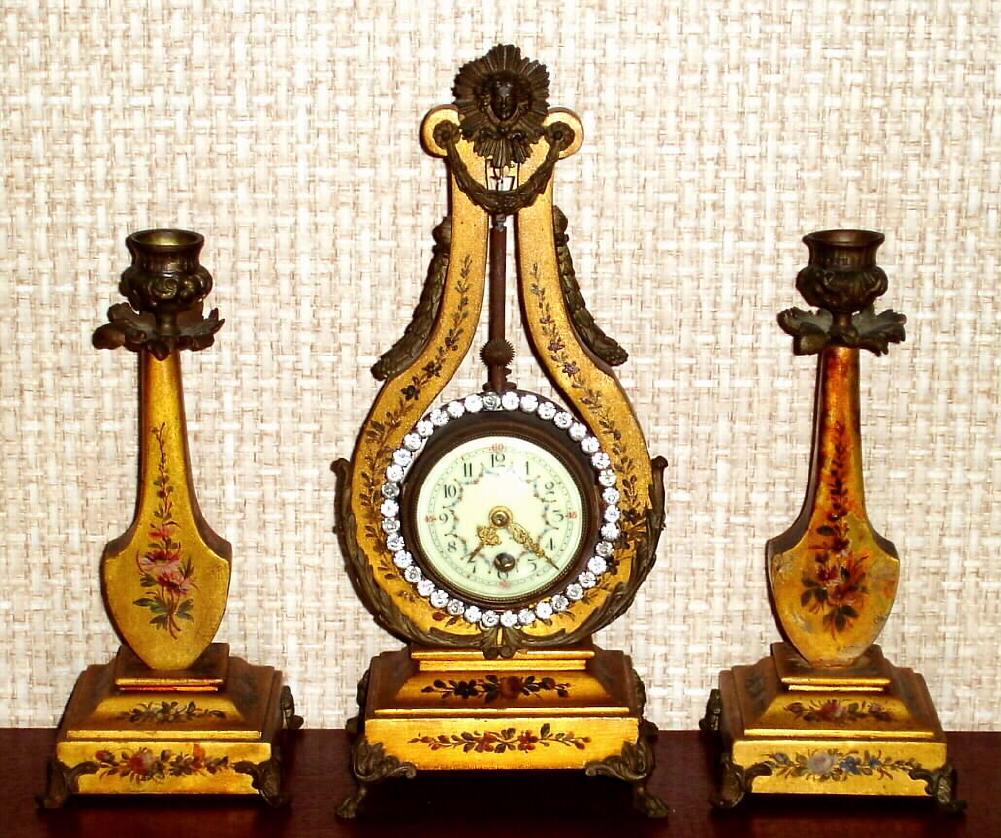 French, Gilt Wood, 3-pc Lyre set, C.1890, small time only pendulum mov't, with swinging brilliant ring, and with 2 matching candle stands, gold leaf with polychrome floral accents. — Antique Clocks Price Guide