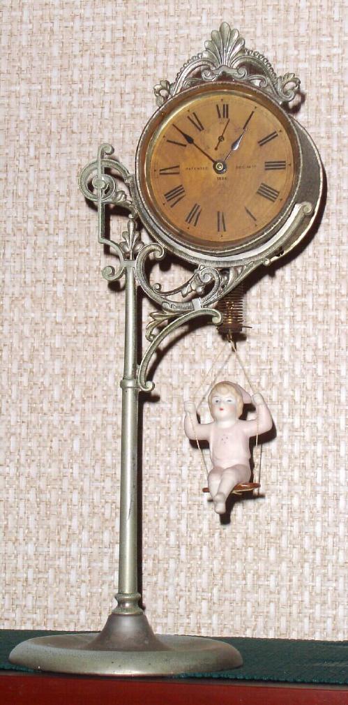 Ansonia Clock Co. New York, "JUMPER NO. 1", C.1896, movement held aloft by a single pole, nickel plated stand, the pin pallet movement released by the ceramic doll jumping up and down. Female doll in light pink. — Antique Clocks Price Guide