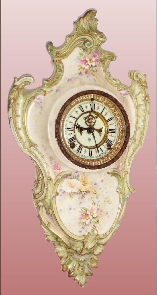 Ansonia Clock Co., C.1906, Royal Bonn, "PORCELAIN HANGING No. 3" china cased wall clock, with floral pattern to case, pendulum movement, gong striking, 8-day. Cream colored case has light green and aqua accents with gold highlights, and multi colored flowers. — Antique Clocks Price Guide