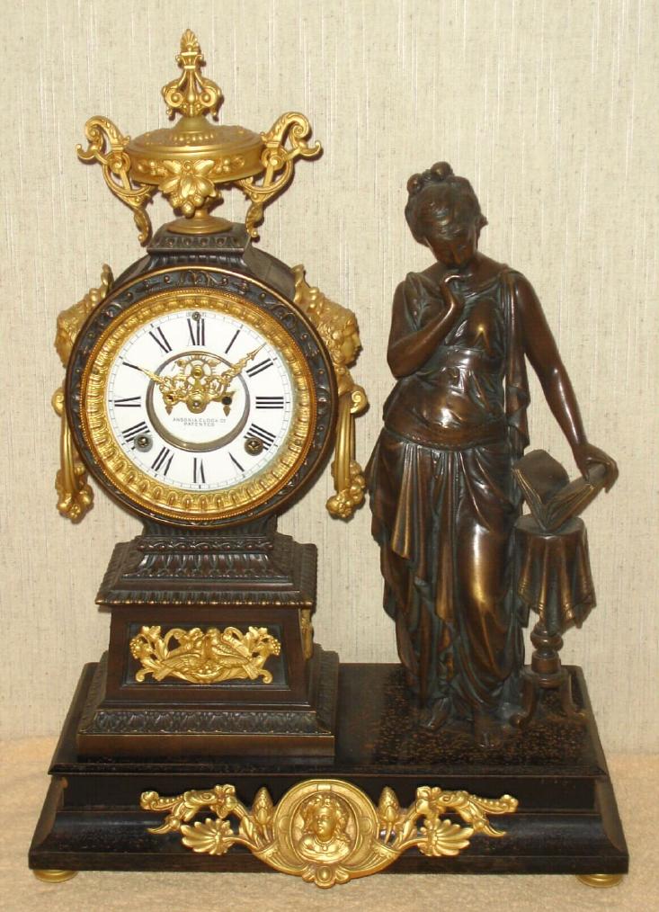 Ansonia Clock Co., New York, C.1880, "POETRY" figure clock, bronze patinated spelter statue and clock tower on a black iron base, with gilt ornaments. Open escapement on porcelain dial. — Antique Clocks Price Guide