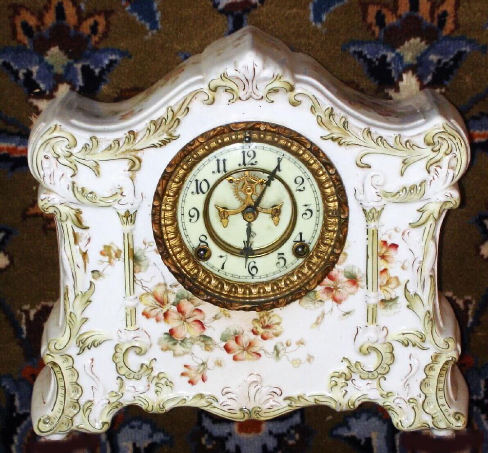 Ansonia Clock Co., Standard Line porcelain china clock, probably a wringer premium from 1910, a creamy colored case, with light green accents and gold highlights, and with brown/ yellow pansy blossoms on top, front and sides. — Antique Clocks Price Guide