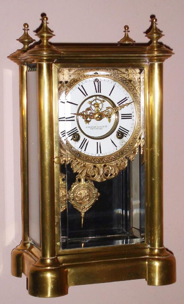 Ansonia Clock Co., Ansonia, Conn. "SYMBOL EXTRA" model crystal regulator 8 day time and unusual strike on dual bells spring driven mvt in rolled brass case with Roman numeral chapter ring and exposed escapement, c1894 — Antique Clocks Price Guide