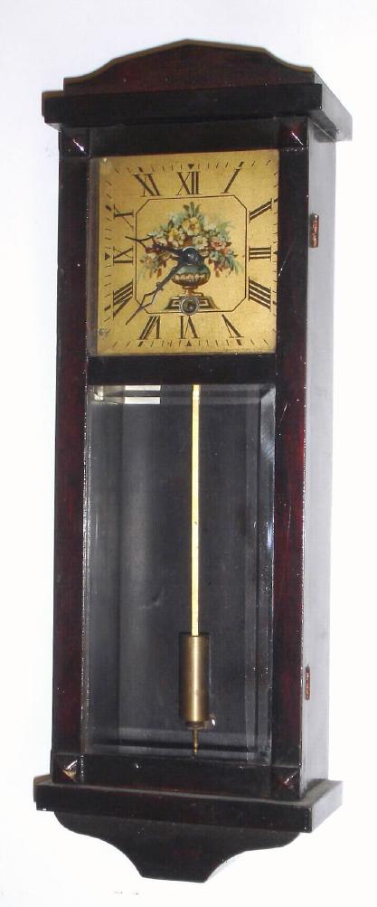 Gilbert Clock Co., miniature "Hollywood" wall timepiece in a mahogany stained poplar case, and with beveled glass in lower door. — Antique Clocks Price Guide