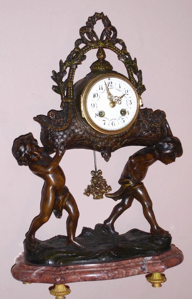 French, Japy Freres, figural clock in white metal case, the 8 day time and strike spring driven clock resting in a floral basket supported by nimble cherubs with a floral basket pendulum on rose and grey mottled marble base with cast brass feet and Arabic numeral polychrome accented 3 1/2" dial, c1890 — Antique Clocks Price Guide