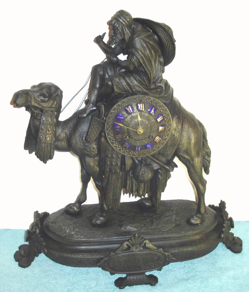 French figural white metal mantel clock, Arabic motif depicting Bedouin at the reins of his blanket clad camel. Dial has applied gilt Roman numerals on blue enamel plaques and base has plaque with Arabic inscription, time and strike on bell 8 day spring driven mvt. {with pendulum} C.1875. — Antique Clocks Price Guide