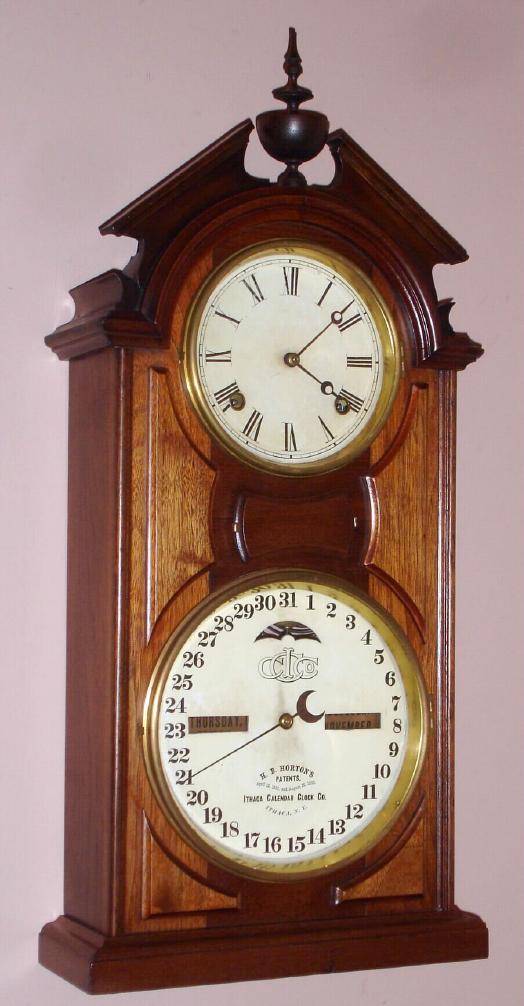 Ithaca Calendar Clock Co., SHELF LIBRARY, walnut cased, 8-day time and gong strike, double dial perpetual calendar with H. B. Horton lower mechanism. — Antique Clocks Price Guide