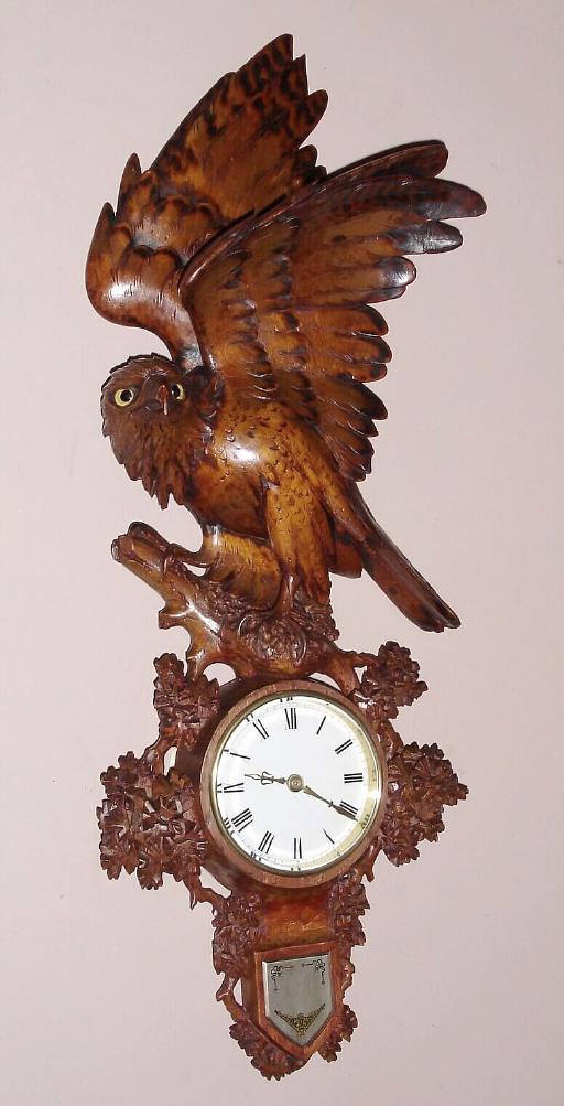 Swiss carved wall clock from the Interlaken region of Switzerland well known for producing these quality carved clocks, unknown hardwood with finely carved eagle peering out with life-like glass eyes perched on roost containing French 8 day time only clock movement with platform lever escapement and Roman numeral porcelain dial, c1900 — Antique Clocks Price Guide