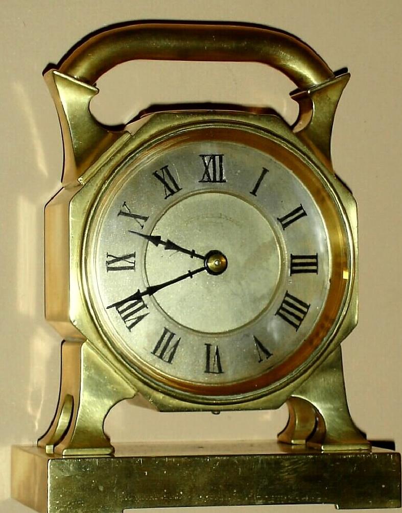 French desk clock in brass case inset with compass on top below large handle with 8 day time only spring driven movement with platform lever escapement and silvered Roman numeral dial, c1910 — Antique Clocks Price Guide
