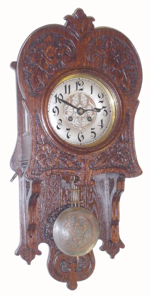 German, Art Nouveau wall clock in oak, with fancy floral pattern dial center and matching pendulum, with a quality solid plate / cut pinion mov't with dead beat escapement. Open well or "Berlin" style case with free swinging pendulum, pressed floral patterns repeated on the door. — Antique Clocks Price Guide