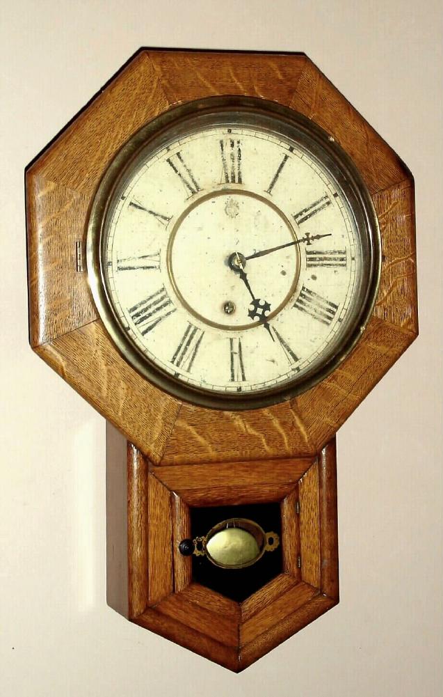 Waterbury Clock Co. Waterbury, Conn. "DROP OCTAGON 10 INCH" wall clock with 8 day time only spring driven mvt in oak veneer case with Roman numeral painted zinc pan 10" dial, C.1910 — Antique Clocks Price Guide