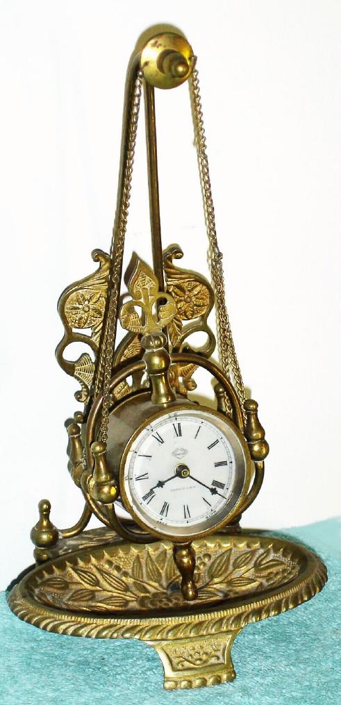 Parker Clock Co., Meriden, Conn, , C.1890, "No. 11" desk timepiece, 1-day, in a well made cast brass case, a trinket tray at bottom, and the clock hanging from 2 chains. — Antique Clocks Price Guide