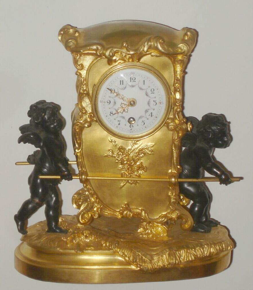 French, c.1880, novelty mantel clock in the form of a gilt sedan, carried by two winged cherubs in black finish, and with a small round movement with platform, serial No. 3678. — Antique Clocks Price Guide