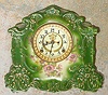 Ansonia Clock Co., C.1905, standard line "RAINBOW" porcelain china cased clock, with 8-day, gong strike mov't with open escapement on porcelain dial, in a medium green case, with multi color floral transfers to the front and sides.