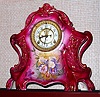 Ansonia Clock Co., Royal Bonn, "LA LAYON", large porcelain clock in the French style, C.1905, with open escapement on the porcelain dial. Color is dark red rose with Iris decorations and profuse gold highlights.