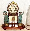H. J. Davies, New York, "CRYSTAL PALACE" C.1875, with original glass dome. 8-day bell strike movement, mounted to a walnut base, with a pair of statues, the barrel pendulum swinging in front of a framed mirror.
