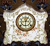Ansonia Clock Co., Standard Line porcelain china clock, probably a wringer premium from 1910, a creamy colored case, with light green accents and gold highlights, and with brown/ yellow pansy blossoms on top, front and sides.