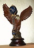 French, Mini Ball Swinger, suspended from a cast and patinated white metal eagle with brass beak, mounted to a turned wooden base.
