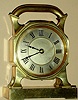 French desk clock in brass case inset with compass on top below large handle with 8 day time only spring driven movement with platform lever escapement and silvered Roman numeral dial, c1910