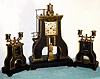 French "STEAM HAMMER" mantel clock from the Industrial series designed by Guilmet, 8-day time and bell strike spring driven movement with applied Roman numeral gilt metal dial, the vertical impact "hammer" serving as the pendulum after the power has been transferred 9 times, sNo. 759, C.1880 including matching steam roller candelabra on black marble base