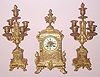 French, C.1880, 3-piece mantle set of brass, cast with scrolls and pilasters and busts on the base, both sides and center. The matching candle stands have 5 lights each, and with cherub busts on the bases.