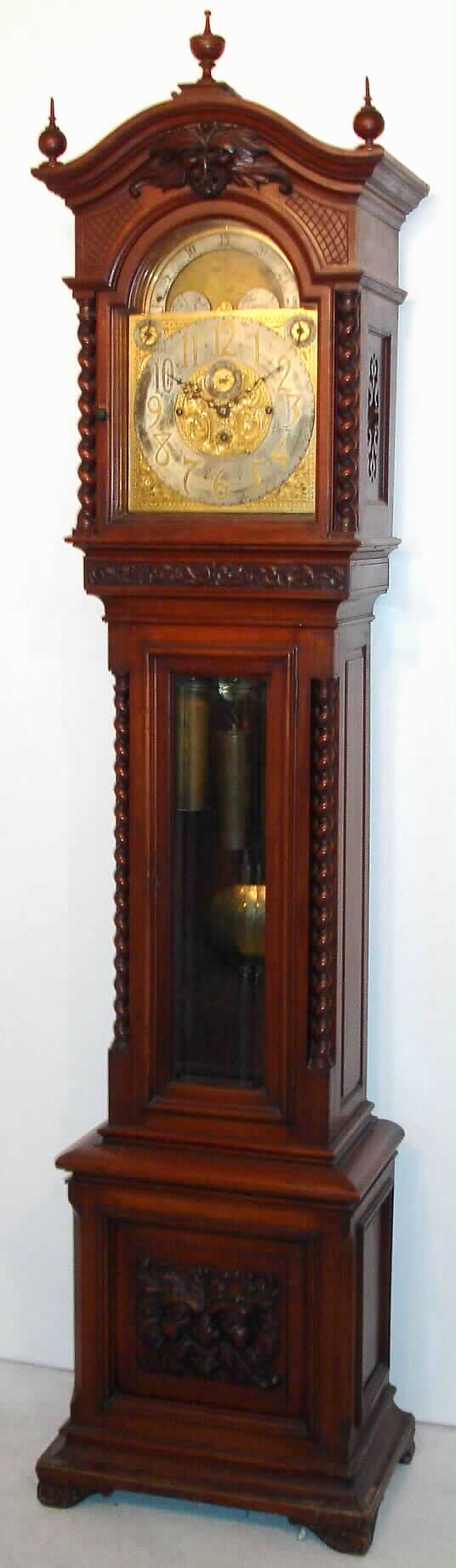 Tiffany and Co., New York, tall case clock, 8 day, quarter chiming, three weight driven movement and playing choice of Westminster chimes on four gongs or Whittington chimes on a nest of 8 bells, in mahogany case with barley twist columns flanking hood and beveled glass door and carvings of the North Wind at the top of the hood and on the front of the base and a brass dial with two discs for silent / strike and Whittington / Westminster and moon phase, c1915 — Antique Clocks Price Guide