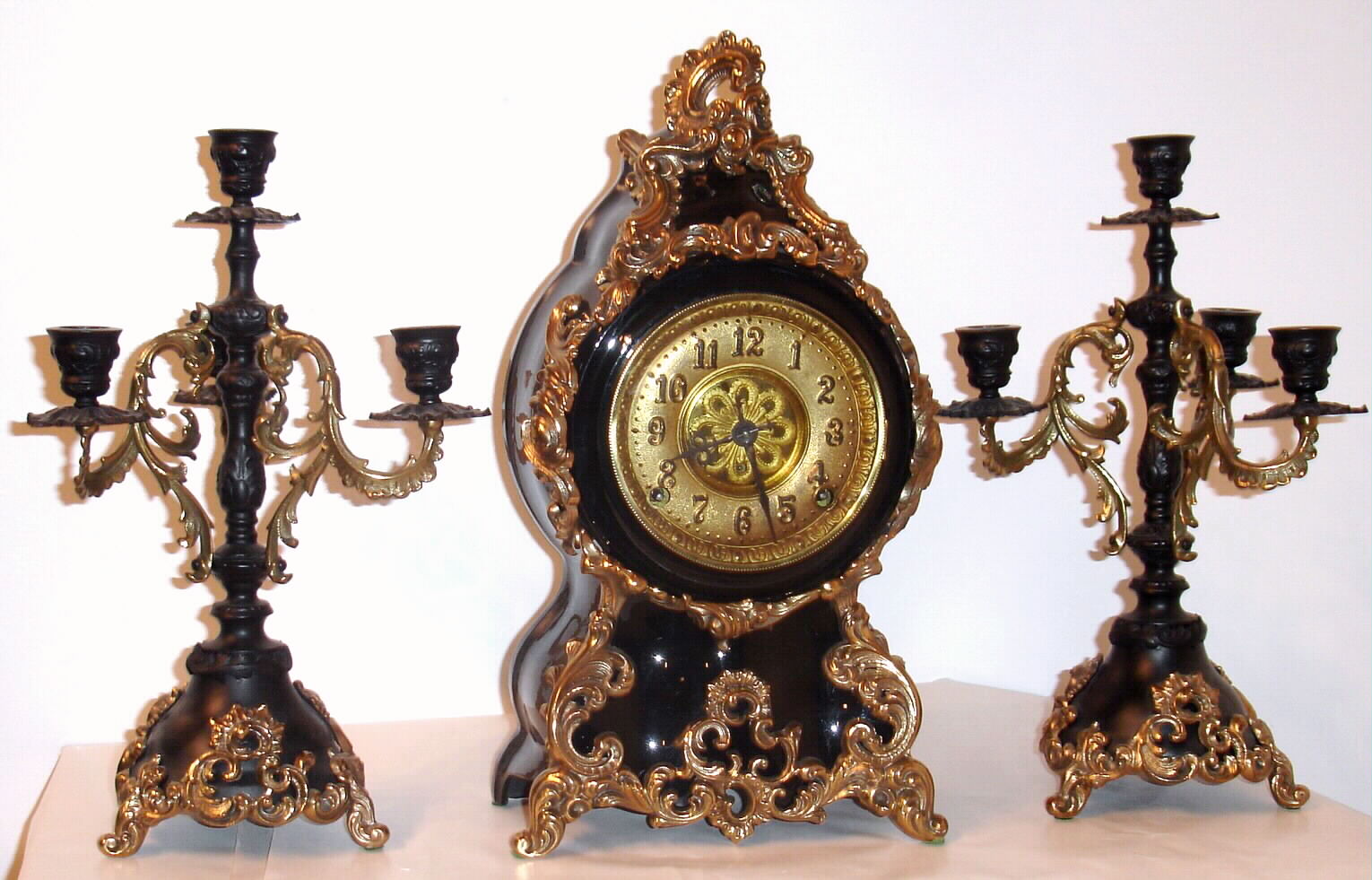 F. Kroeber Clock Co., New York, "Louis XIV" three piece garniture set with 8 day time and strike spring driven movement in black enamel cast iron case with polished brass appliquEs and matching black enamel and brass cast iron candelabra, c1895 — Antique Clocks Price Guide