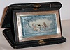 Travel clock Swiss 8 day in silver case with painted ivory Arabic numeral dial decorated in two tone scene of lovers reclining and playing music, c1920 including outer leather travel case