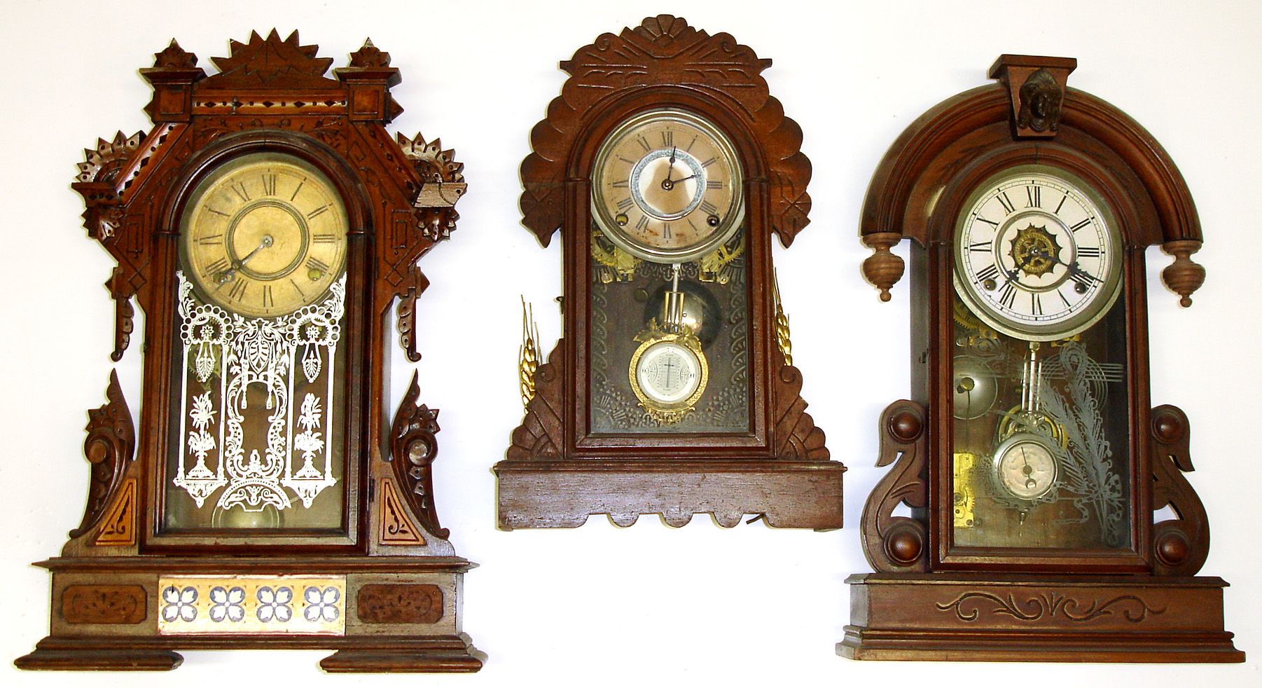 Three mahogany case 8-day Connecticut parlor clocks. One Kroeber with beveled glass pendulum, one Waterbury "Paris" with alarm. Tallest, with nice glass and lower floral panel and alarm, is 22" high. — Antique Clocks Price Guide