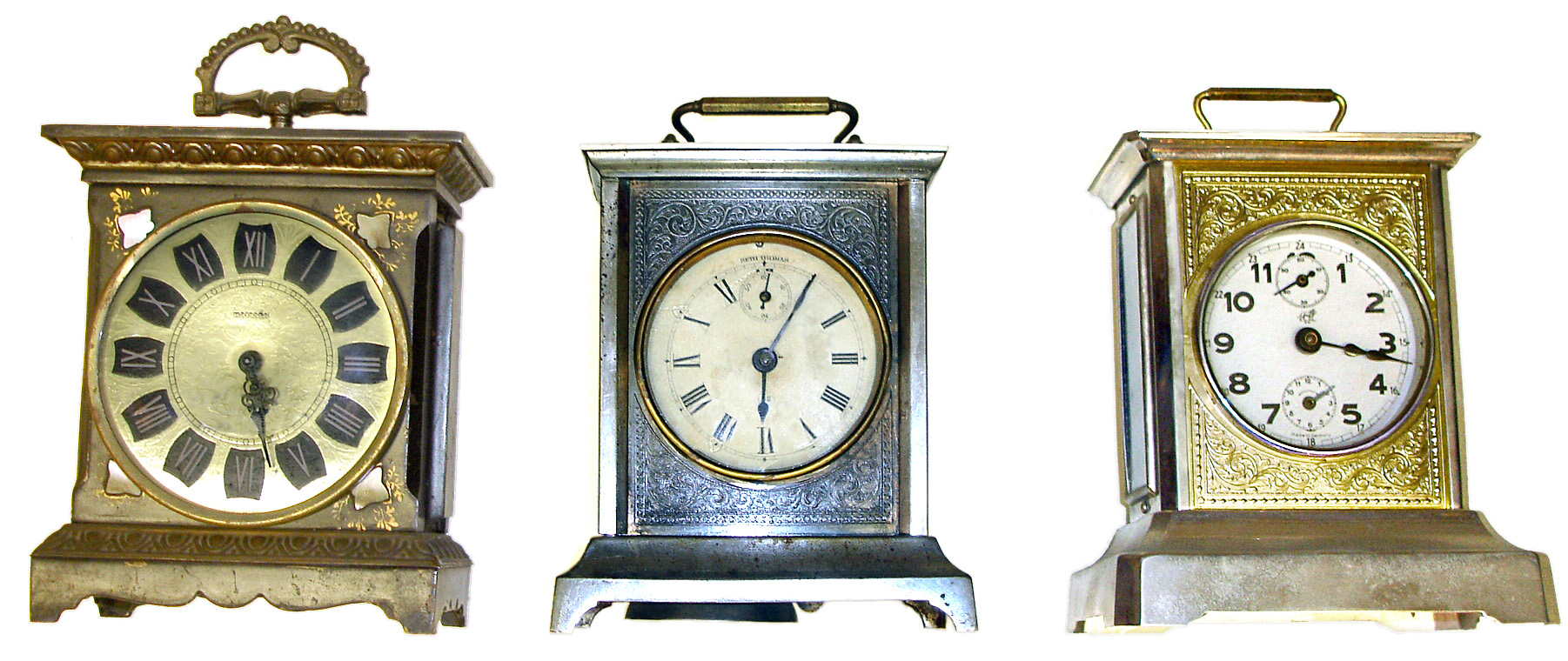 Three traveling clocks with top handles. Best and oldest is Seth Thomas striker with seconds bit and embossed front mask. Other 2 are modern Germans, one with alarm and other is Mercedes with MOP inlays. Tallest is 8" high. — Antique Clocks Price Guide
