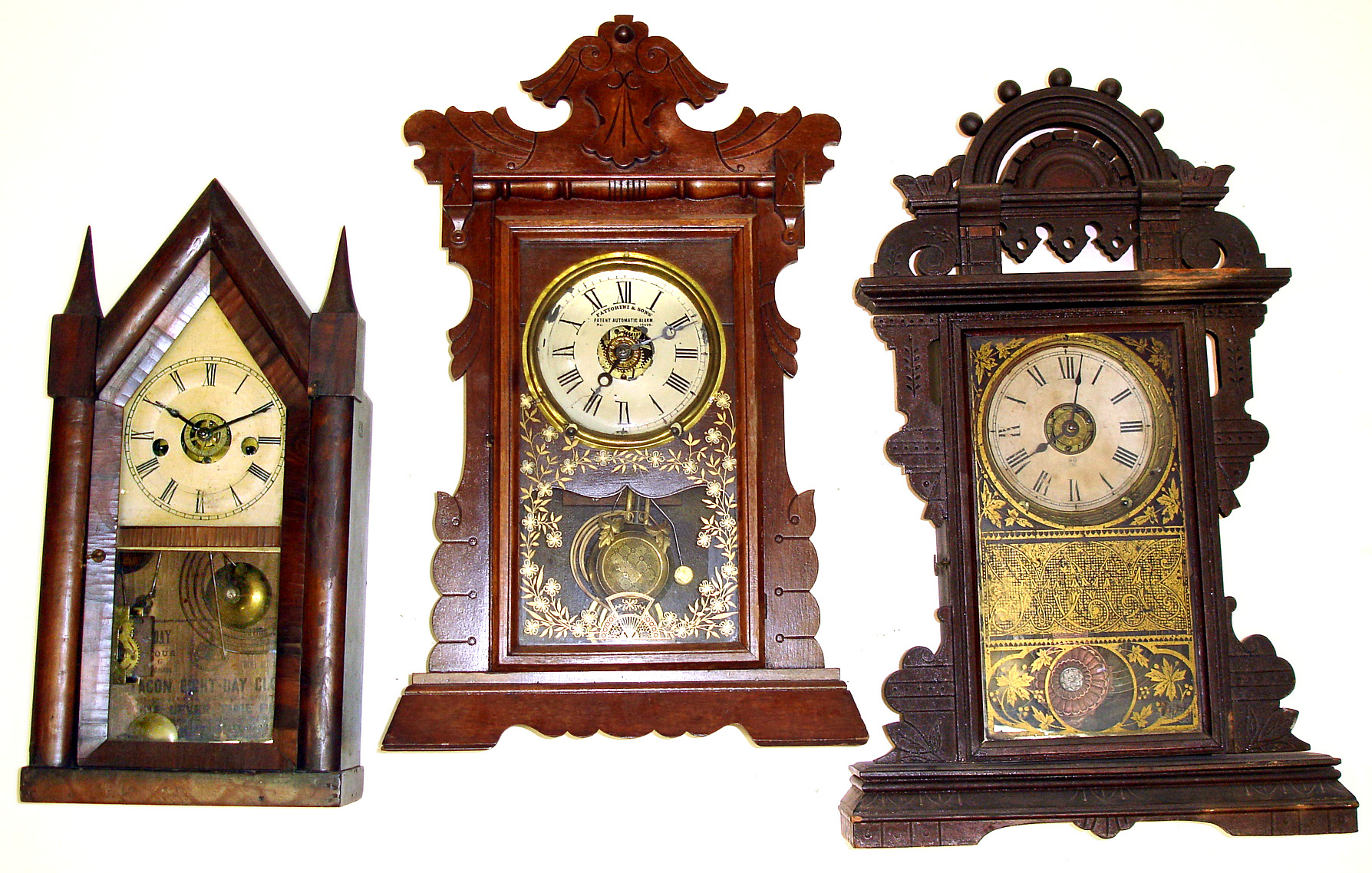 Three wood case shelf clocks. One English 8 day Fattorini and Sons mahogany "Patent Automatic Alarm". One 30 hour Chauncey Jerome early steeple with conical finials. Tallest, Seth Thomas parlor clock with Eclipse pendulum and alarm, is 24" high. — Antique Clocks Price Guide