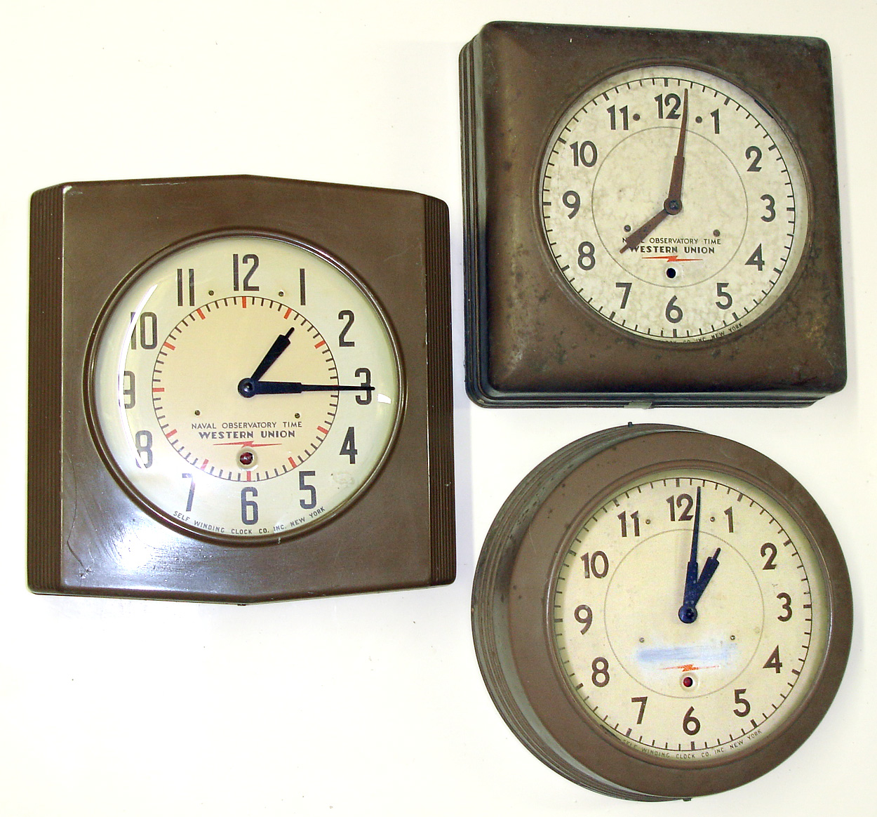 Three Western Union Self Winding Clock Co. gallery clocks. Electrically wound movements. These clocks were leased for distribution of standard "Naval Observatory Time". One square (no glass), one round, one unusual square with reeded sides and slightly pointed top and bottom. 11" dials. — Antique Clocks Price Guide