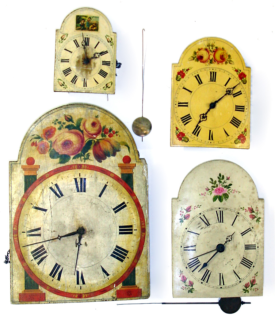 Four Black Forest shield front weight driven wall clocks. Brightly painted dials, wood plate movements, two have bells on top. Smallest with cute little painting of shepherds is 8" high. Largest, with bold columns and flowers, is 18" high. — Antique Clocks Price Guide