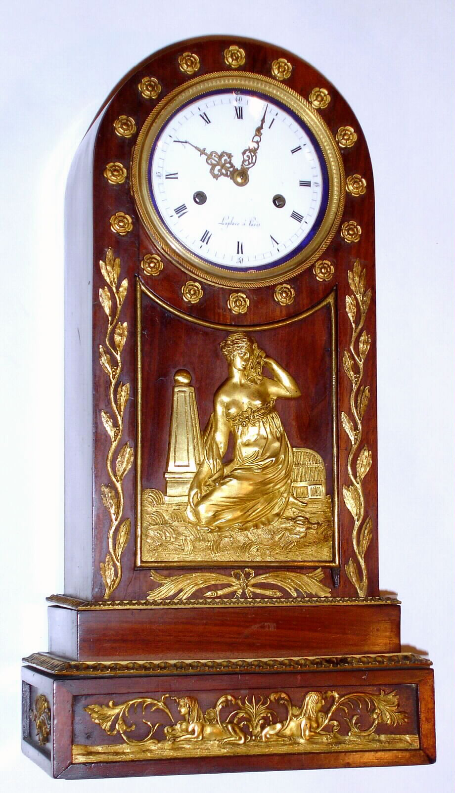 French, Empire style mahogany mantle clock, featuring a central frieze with a bare breasted maiden next to an obelisk surmounted by a globe. The base of the case with Egyptian themes, two sphinx with the head of Cleopatra. Bell strike movement has silk thread suspension. Dial signed LaPlace, Paris, c1840 — Antique Clocks Price Guide