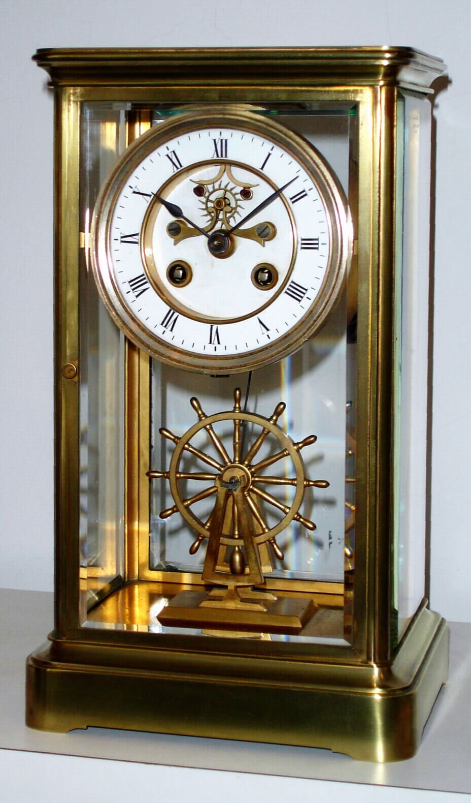 French, 4-glass crystal regulator with uncommon detached balance wheel in the form of a ship's wheel, the wheel rolling a carriage mounted to the base of the case, and a long crutch extending to an impulse pin on the rear of the wheel . The escapement, with large ruby jewels, is visible on the dial, c1900 — Antique Clocks Price Guide