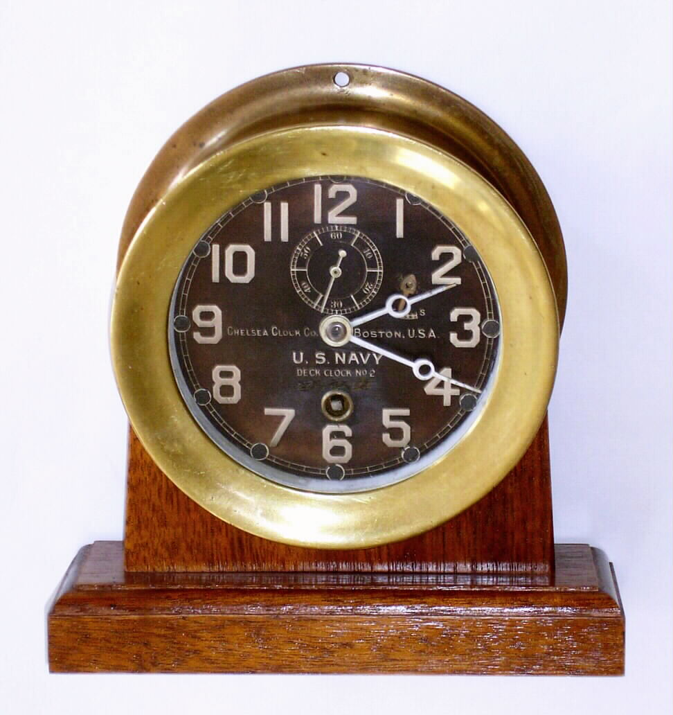 Chelsea Clock Co., Boston, USA, 4.5" black dial naval timepiece, with formerly luminous hands, now painted white, bearing serial number 128960, c1942. Includes a later mahogany desk stand. — Antique Clocks Price Guide