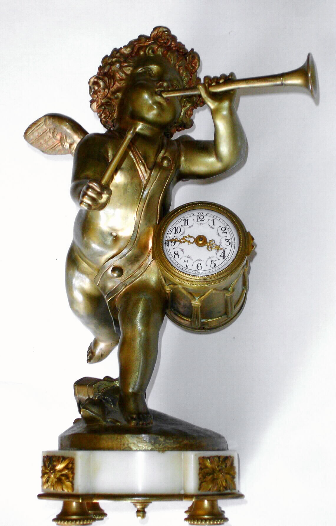 French, bronze and marble mantle clock depicting a winged cherub playing a trumpet and with a drum stick in his right hand, the drum resting against his left side and containing a tiny round movement with cylinder platform and gilt hands, c1880 — Antique Clocks Price Guide