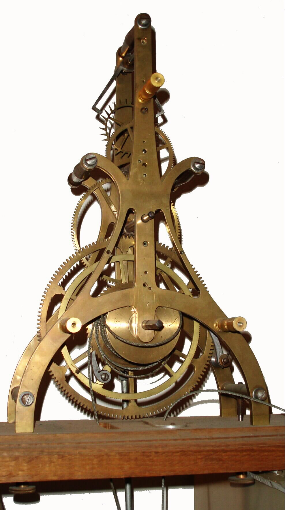 English, Street or small tower timepiece movement, nice scroll frame, and with Graham's dead beat escapement (jeweled pallets) and maintaining power, complete with a canister style pendulum (no mercury) and large brass covered weight, no hands nor dial, eight day duration (need several feet for weight to drop), mounted to a molded edge plank of oak, and probably meant for a window display. C.1900. — Antique Clocks Price Guide