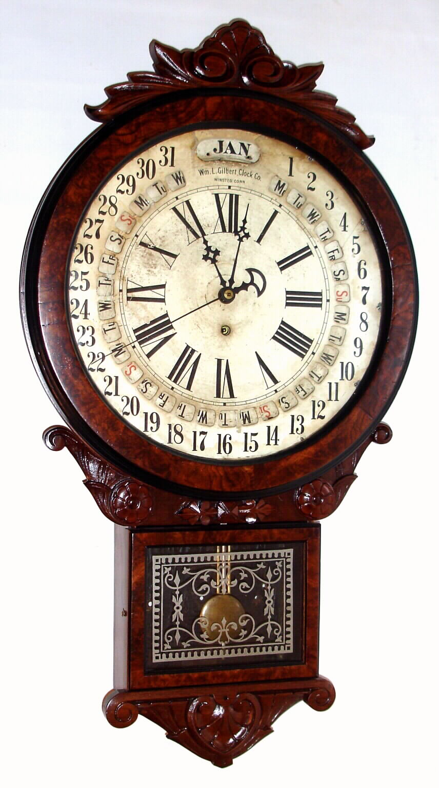 William L. Gilbert Clock Co., "Office Drop Calendar" 8-day with Maranville type rotating disc simple calendar with month and days of the week, in a walnut case with carved trim and burled walnut veneer accents. Note Gilbert used paper discs, moved by a pointer to evade the Maranville patent. c.1881 — Antique Clocks Price Guide
