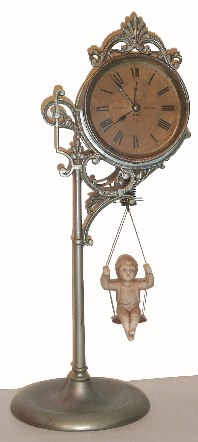 Ansonia Clock Co., "Jumper No. 1", 30 hour bobbing doll novelty timepiece. Movement supported by a single pole, nickel plated stand, the pin pallet movement runs by the action of the ceramic doll bobbing up and down. Doll is a replacement. c.1894 — Antique Clocks Price Guide