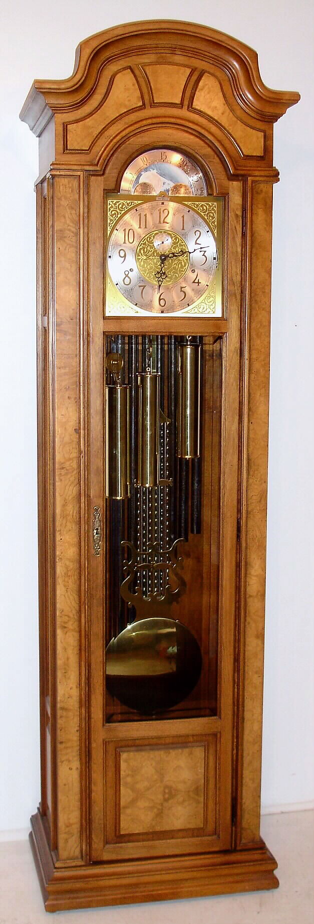 Howard Miller, Zeeland, Michigan, modern tall clock 8 day time, strike and chime on 9 tubes with option for Westminster, Whittington or St. Michael's tune weight driven movement in hard wood case with silvered metal dial with moon phase and applied brass numerals and spandrels, c1995 — Antique Clocks Price Guide