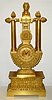 French, Empire style lyre mantel clock, with knife edge suspension of pendulum above the dial, 8 day spring, movement numbered 210. The case profusely decorated with acanthus leaves, pineapples to the right and left of the top, and each column surmounted by a small urn with floral display, c1830