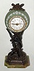 French, miniature timepiece in a light green Wedgewood case, resting on a patinated spelter stand (pole with a torch bearing winged man), the whole resting on a green onyx base. A small round French movement has a tiny lever platform [yes], in good order, c1900
