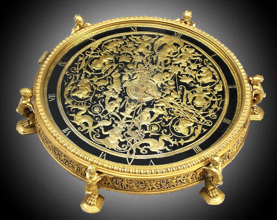 E.F. Caldwell, N.Y. table clock with Greco-Roman Classical theme. The E. Howard and Co., Boston, 8 day, time only, spring driven, nickel damascene movement has a lever escapement and micrometric regulator, s#2531, and is housed in a large gilt and patinated bronze circular case with six legs in the form of winged satyrs raising the case about 1 1/4" off the ground. The back plate is engraved in script "E.F. Caldwell and Co. Inc. New York". The dial facing upwards is highly ornate with Classical decor including finely cut and engraved mythological figures and animals, c1915 — Antique Clocks Price Guide