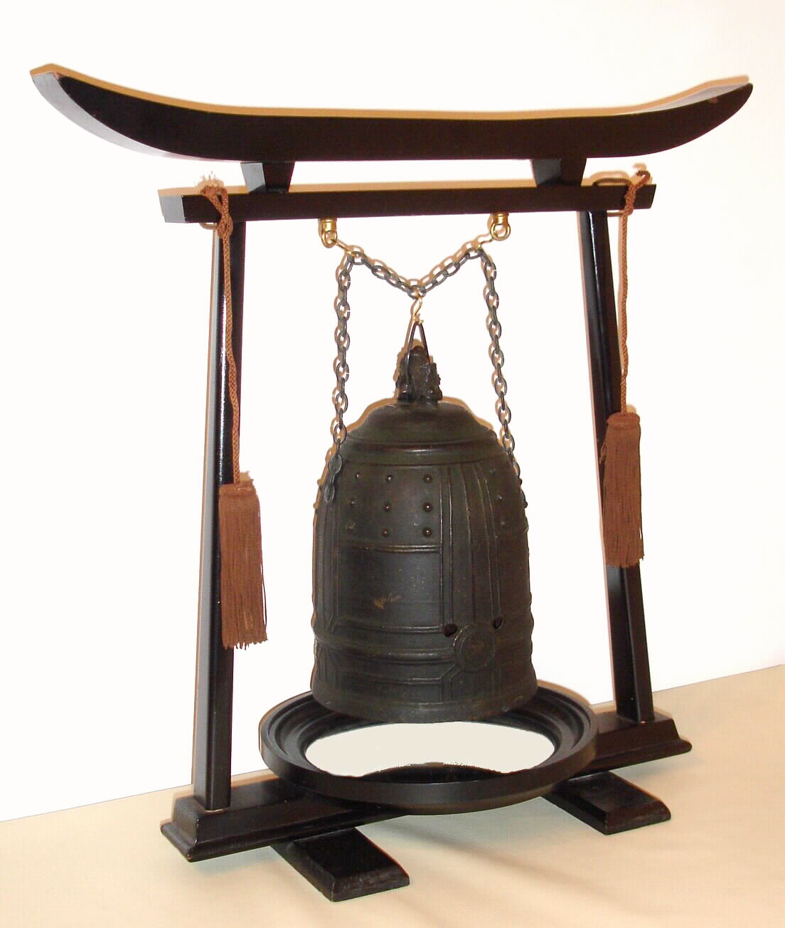A rare and early Japanese bell clock (Tsurigane Dokei) within a finely cast bronze bell with Japanese characters and double headed dragon form handle; having a posted, iron, double spring driven, striking movement with crown wheel escapement and time regulated by a large circular balance with moveable double weights, originally for adjusting the temporal hours every day before each sunrise and sunset with the change of each Japanese season. The brass dial with single, fixed hand has traditional Japanese numerals 9 through 4 with applied silvered butterflies to the original surrounding dial plate. The rotating dial with adjustable "hour" and "half hour" markers is a common 19th Century upgrade to many very early Japanese clocks that have a single foliot or balance, since changing the weights and hence the rate before sunrise and sunset each day was extremely unhandy. This is verified by J. Drummond Robertson in The Evolution of Clockwork , page 226 saying "we find some of the old clocks "converted" to the new style of motion work. The old fixed hour circle with its revolving centre was removed and the new revolving circle and its fixed hand with adjustable "hour" plates was substituted." This is the case in each of the only other examples of Japanese Bell Clocks of which we are aware: see Japanese Clocks by N.H.N. Mody, plate 113, fig.1 for an almost identical example to the clock being offered. This dial conversion is also apparent in the Bronze Bell Clock sold at Sotheby's Masterpieces From the Time Museum Sale, Part Two, 19 June 2002, lot 126. An inscription on the bell reads Fukushima ya Katsutaro 1689, who may be the maker of either the clock or the bell. Most Japanese spring driven clocks have a fusee to the time train and a going barrel to the strike train. This movement is anomalous, in that is has two going barrels. It may be that the Japanese had not developed a method of turning a fusee at this early date, C.1690 — Antique Clocks Price Guide