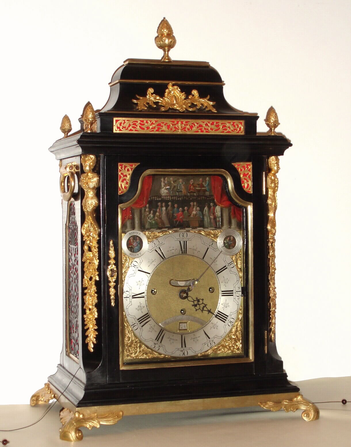 Step'n Rimbault, London, 6-tune musical bracket clock with automaton and calendar, 8 day, time, strike and music on a nest of 14 bells with large horizontal finely pinned drum, in an ebonized walnut or mahogany Georgian case with gilt caryatids to the front corners. The dial has a silvered Roman numeral chapter ring, indicators for strike / silent and tune names, date aperture, mock pendulum aperture and silvered ribbon with maker's signature all eclipsed in the arch by a two-level painted dinner party scene where two figures come from the wings of the scene and dance across the center, as the music plays. The music ensemble is on the upper level in the arch, c1770 — Antique Clocks Price Guide