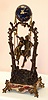 French, very large swing clock, Patinated spelter tree limbs entwined at the top to form the support for the swinging clock. A romantic couple are seated in a swing, appearing to suspend by rope, The original marble base with a brass title plaque: "Idylle Printaniere, par Geo Maxim", the couple swinging from side to side without apparent impulse, c1890