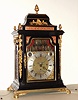 Step'n Rimbault, London, 6-tune musical bracket clock with automaton and calendar, 8 day, time, strike and music on a nest of 14 bells with large horizontal finely pinned drum, in an ebonized walnut or mahogany Georgian case with gilt caryatids to the front corners. The dial has a silvered Roman numeral chapter ring, indicators for strike / silent and tune names, date aperture, mock pendulum aperture and silvered ribbon with maker's signature all eclipsed in the arch by a two-level painted dinner party scene where two figures come from the wings of the scene and dance across the center, as the music plays. The music ensemble is on the upper level in the arch, c1770