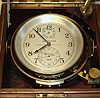 Hamilton Watch Co., Lancaster, PA, Model 21 marine chronometer with 56 hour up/down indicator, 85 size,14J, key wind, chain fusee driven damascene nickel movement with spring detent escapement, giant uncut AMAC solid monometallic weighted chronometer balance, free sprung Elinvar class helical hairspring system and balance lock for hacking or shipping located next to winding hole, operated by allen wrench (included) The silvered 4 1/8" Arabic numeral dial is engraved "HAMILTON LANCASTER PA., U.S.A. N3460 1941" and has blacked steel hands, s#2E3460. The lot includes the original gimbaled inner dark red mahogany stained box with full brass banding, corners, handles and central tongue in groove seal with Hamilton tag, original key and setting instructions